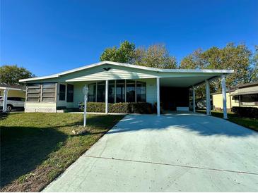 Inviting single-story home featuring a spacious carport and well-manicured lawn under a sunny sky at 607 Webb Way, The Villages, FL 32159