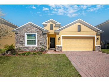 Charming single-Gathering home with a well-manicured lawn, stone accents, and a two-car garage at 1041 Bradford Ridge Dr, Leesburg, FL 34748