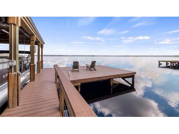 Scenic view of a boat dock with chairs, a lift, and beautiful water views, ideal for lakeside relaxation at 12117 Cypress Ln, Clermont, FL 34711