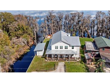 Stunning two-story home with metal roof and inviting front porch overlooking the lush lawn and waterfront at 12117 Cypress Ln, Clermont, FL 34711