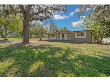 Charming single-story home with well-kept lawn and inviting front porch, shaded by mature trees at 211 Sara Ln, Leesburg, FL 34748