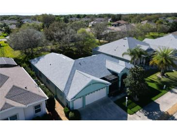 Aerial view of charming single-story home featuring a screened lanai, lush landscaping, and attached two car garage at 25517 Laurel Valley Rd, Leesburg, FL 34748