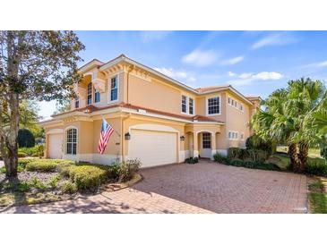 Charming two-story home featuring a three-car garage, tile roof, manicured landscaping, and a brick paved driveway at 26207 Avenida Las Colinas # 13A, Howey In The Hills, FL 34737