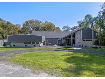 Beautifully designed home with stone accents, gray siding and a well-manicured lawn under a clear blue sky at 36014 Poinsettia Ave, Fruitland Park, FL 34731