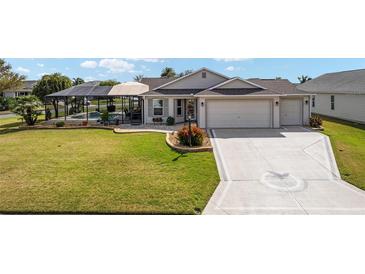 Charming single-story home boasts a well-manicured lawn, screened-in pool, and a spacious two-car garage at 592 Netherwood Pl, The Villages, FL 32163