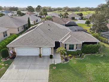 Stunning home featuring a well-maintained lawn, an attached two car garage, and beautiful landscaping at 610 Espana St, The Villages, FL 32159