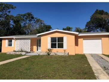 Charming single-story home with an orange exterior, white trim, a well-manicured lawn, and an attached garage at 616 N Hartley Cir, Deltona, FL 32725