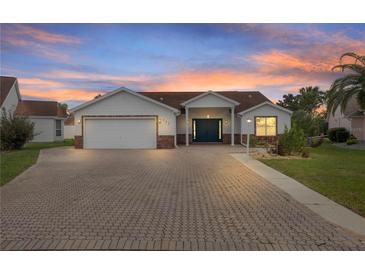 Charming single-story home featuring a brick-paved driveway, well-maintained landscaping, and an attached two-car garage at 723 Palma Dr, Lady Lake, FL 32159