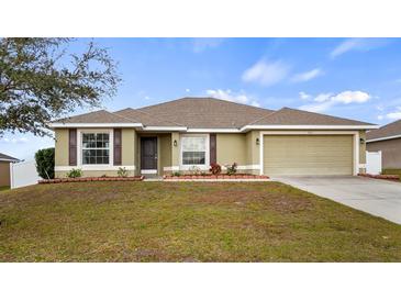 Charming single-story home features a two-car garage, simple landscaping, and a well-maintained lawn at 902 Chestnut Dr, Fruitland Park, FL 34731