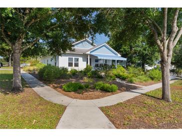 Charming home featuring a blue awning, complemented by lush landscaping and a welcoming walkway at 1013 Lake Elsie Dr, Tavares, FL 32778