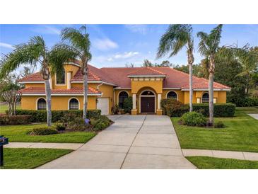 Stunning Mediterranean-style home with a red tile roof, a welcoming entrance, and lush tropical landscaping at 12127 Cypress Landing Ave, Clermont, FL 34711