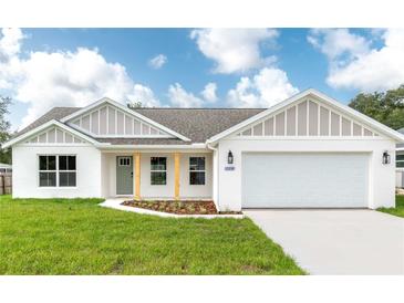 Charming single-story home with a well-manicured lawn, two-car garage, and a welcoming light-green front door at 13334 Sw 107 St, Dunnellon, FL 34432