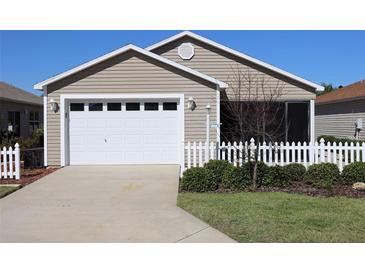 Charming home with a well-manicured front yard, white picket fence, and attached two-car garage at 1805 Endsley Ct, The Villages, FL 32162