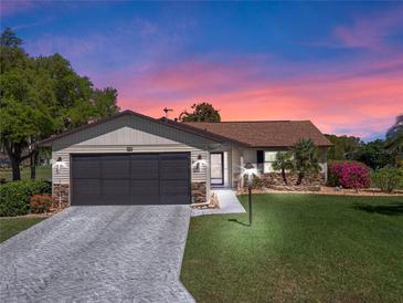 Charming single-story home featuring a two-car garage, stone accents, and a well-manicured lawn with beautiful landscaping at 26636 Evert St, Leesburg, FL 34748