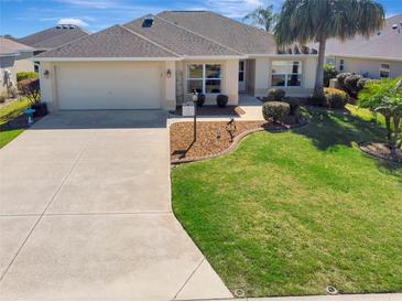 Well-maintained home with a landscaped front yard, a paved driveway, and an attached two-car garage at 3405 Rabbit Run Path, The Villages, FL 32163