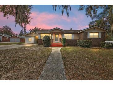 Charming single-story brick home with a walkway leading to a welcoming red porch and mature landscaping at 448 E Waldo St, Groveland, FL 34736