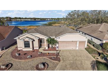 Lovely waterfront home featuring a well-maintained lawn, two-car garage, and picturesque lake views at 4818 Sawgrass Lake Cir, Leesburg, FL 34748