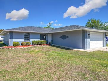Charming single-story home featuring well-maintained lawn, manicured bushes, and a two car garage at 4857 Se 137Th Pl, Summerfield, FL 34491