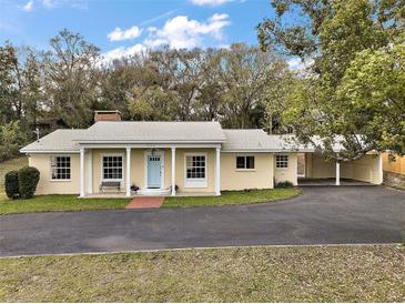 Charming single-story home with a blue front door, well-manicured lawn, and convenient covered parking at 502 Lake Gracie Dr, Eustis, FL 32726