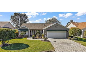 Charming single-story home features a well-manicured lawn, lush landscaping, and a brick-paved driveway at 776 Alcott Ave, The Villages, FL 32162