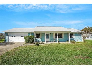 Charming single-story home with a well-maintained lawn and attached garage, painted in a cheerful blue hue at 1033 Scotch Pine Ct, Leesburg, FL 34788