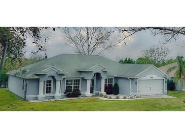 Charming single-story home with blue exterior, white trim, well-manicured lawn, and an attached two-car garage at 11727 Pineloch Loop, Clermont, FL 34711