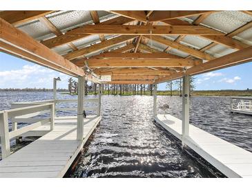 Covered boat dock featuring a white wooden pier and exposed beams, overlooking the sparkling water at 1401 W Highway 50 # 173, Clermont, FL 34711
