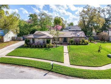 Beautifully landscaped front yard with lush green lawn and mature trees surrounding a well-maintained single-story home at 1494 Grace Lake Cir, Longwood, FL 32750