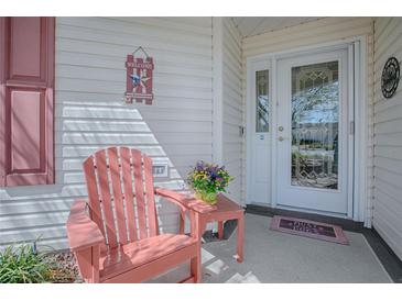 Inviting front porch featuring a decorative door and a cozy chair with a side table at 17714 Se 84Th Sheldon Ter, The Villages, FL 32162