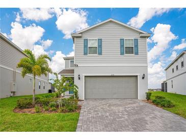 Charming two-story home with light gray siding, blue shutters, and a meticulously paved driveway at 2116 Lelani Cir, Davenport, FL 33897