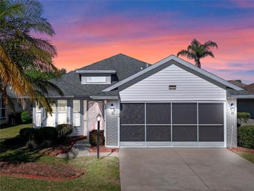 Charming single-story home featuring a screened two-car garage, brick accents and lush landscaping at 4712 St Andrews Arc, Leesburg, FL 34748