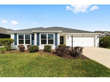 Charming one-story home with white siding, well-manicured lawn and blue shutters at 5978 Conley Ct, The Villages, FL 32163