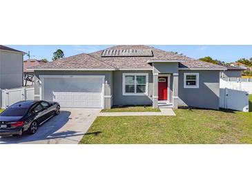 Charming one-story home featuring a red front door, garage, and well-manicured lawn at 717 Robin Ct, Kissimmee, FL 34759