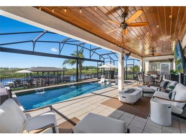 Gorgeous covered outdoor pool and patio with ample seating, a built in bar, and waterfront views at 724 Barefoot Bay Loop, Groveland, FL 34736