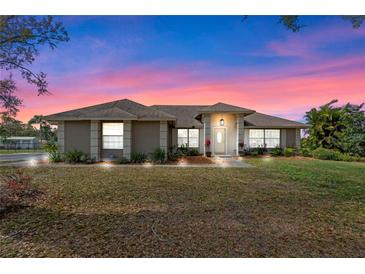 Beautiful single-story home with a well-maintained lawn and mature landscaping, set against a vibrant twilight sky at 7729 Lake Andrea Cir, Mount Dora, FL 32757