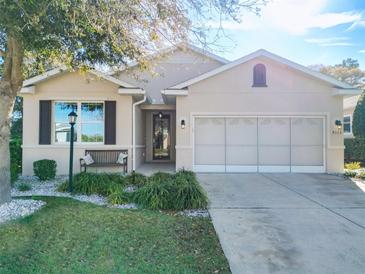 Charming single-story home with a well-manicured lawn, a bench, and an attached two-car garage at 9113 Sw 91St Court Rd, Ocala, FL 34481
