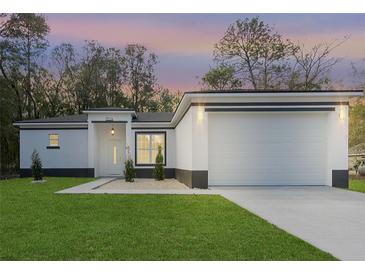 Charming single-story home featuring a well-manicured lawn, a two-car garage, and classic architectural details at 12255 Sw 98Th St, Dunnellon, FL 34432
