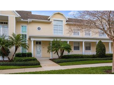 Charming yellow townhome with a well-manicured lawn, lush landscaping, and a welcoming front porch with white columns at 164 Nautica Mile Dr, Clermont, FL 34711