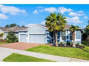 Charming single-story home with a well-manicured lawn, brick driveway, and beautiful palm trees at 17024 Goldcrest Loop, Clermont, FL 34714