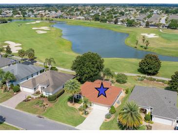 Stunning aerial view of a home on a golf course with a serene lake, surrounded by lush greenery and mature trees at 2068 Darlington Dr, The Villages, FL 32162