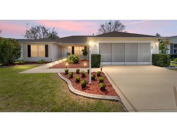 Charming home featuring a manicured lawn, tidy landscaping, and accent lighting creating an inviting curb appeal at 2712 Benavides Dr, The Villages, FL 32162