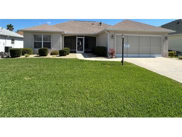 Well-maintained single-story home featuring a lush green lawn and manicured shrubbery at 3183 Hatch Ln, The Villages, FL 32162