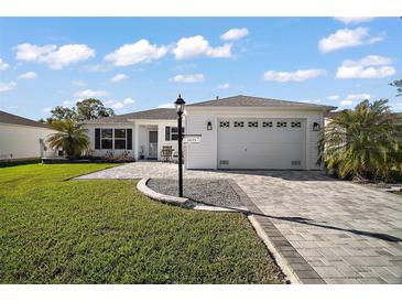 Charming one-story home showcasing manicured landscaping and a welcoming, paved driveway leading to the garage at 3655 Idlewood Loop, The Villages, FL 32162