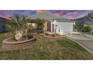 Charming home featuring manicured lawn, decorative landscaping, and a two-car garage with an upgraded driveway at 3786 Stephanie Way, The Villages, FL 32163