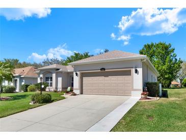 Charming single-story home with a well-maintained lawn, beige stucco, and two-car garage at 5645 Huntington St, Leesburg, FL 34748