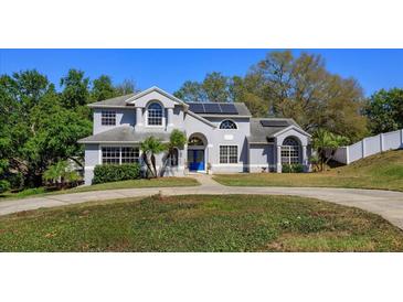 Inviting home with solar panels boasts a lush, green lawn, creating a picturesque setting at 12815 Katherine Cir, Clermont, FL 34711