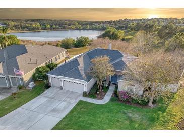 Beautiful single Gathering home featuring lush green lawn, a three-car garage and lake views at 13131 Sandy Pine Ln, Clermont, FL 34711