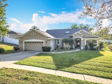 Charming single-story home with a well-manicured lawn, two-car garage, and inviting front entrance at 13421 Via Roma Cir, Clermont, FL 34711