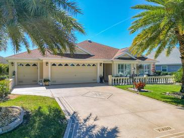 Charming home featuring a three-car garage, beautifully landscaped yard, and inviting front porch at 1430 Hillstream St, The Villages, FL 32163