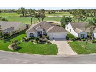 Beautiful single-story home featuring a well-manicured lawn, lush landscaping, and a three-car garage near the golf course at 1726 Augustine Dr, Lady Lake, FL 32159